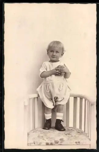 Foto-AK Kleinkind mit Ball auf einem Stuhl stehend