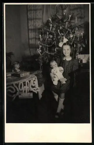 AK Mädchen sitzt mit Puppe auf dem Schoss an einem Weihnachtsbaum