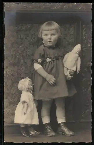 Foto-AK Kleinkind mit einer Puppe im Arm und einer anderen Puppe daneben