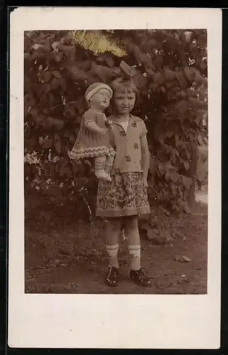 Foto-AK Junges Kind im Garten mit einer Puppe auf dem Arm