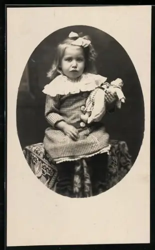Foto-AK Junges Kind mit Schleife im Haar und einer Puppe im Arm