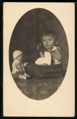 Foto-AK Kleinkind sitzt in einem Korb, daneben eine Puppe