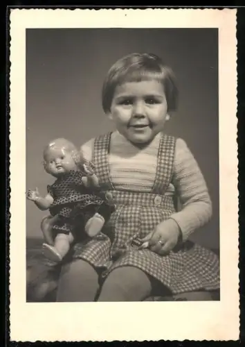 Foto-AK Kleinkind in kariertem Kleid mit Puppe im Arm
