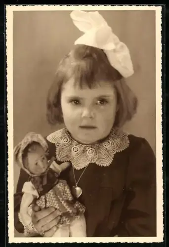 AK Kleinkind mit Schleife im Haar und einer Puppe