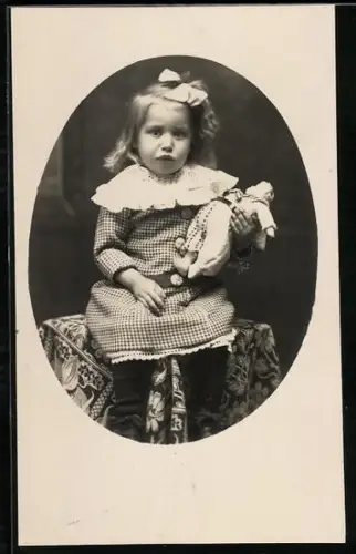 Foto-AK Mädchen sitzt auf einem Tisch und hält ihre Puppe im Arm