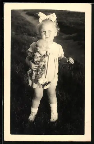 Foto-AK Kleinkind mit Schleife und Puppe im Garten