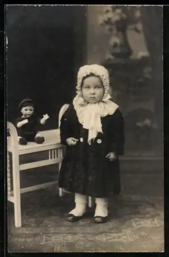 Foto-AK Kleinkind mit Haube neben einer Puppe