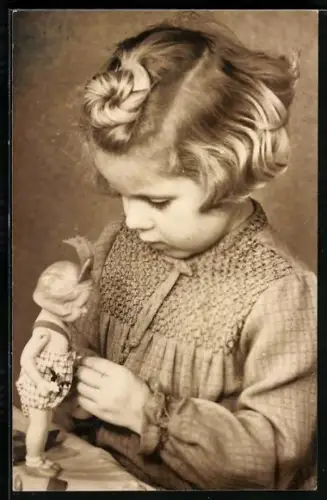 AK Mädchen schaut konzentriert zu ihrer Puppe