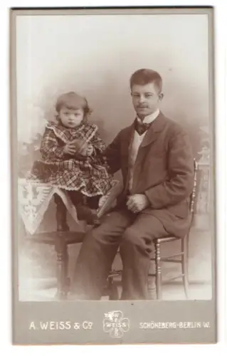 Fotografie A. Weiss & Co., Schöneberg-Berlin, Hauptstr. 14, Kind auf Tisch mit Mann