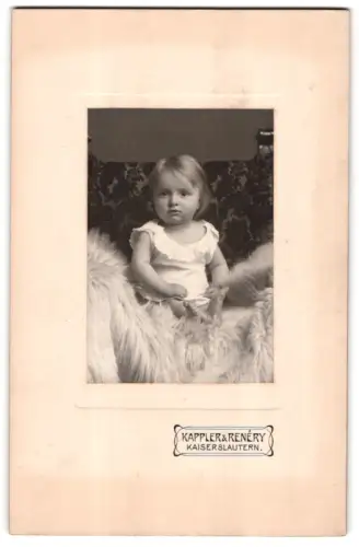 Fotografie Kappler & Renéry, Kaiserslautern, Kind im weissen Kleid auf Fell