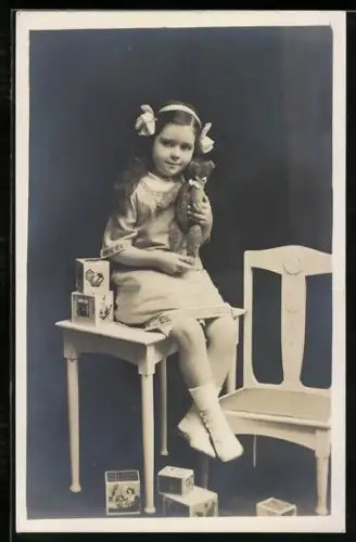 Foto-AK Mädchen mit Bausteinen und Teddy auf einem Tisch sitzend