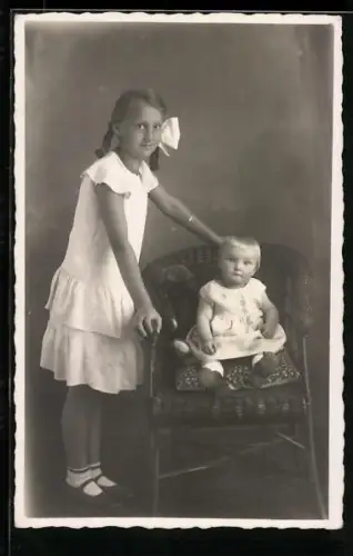 Foto-AK Zwei Geschwister mit einem Teddy auf einem Stuhl