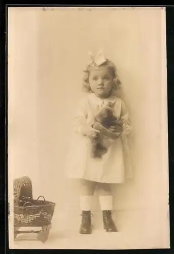 Foto-AK Mädchen mit Schleife im Haar hält einen Teddy in den Armen