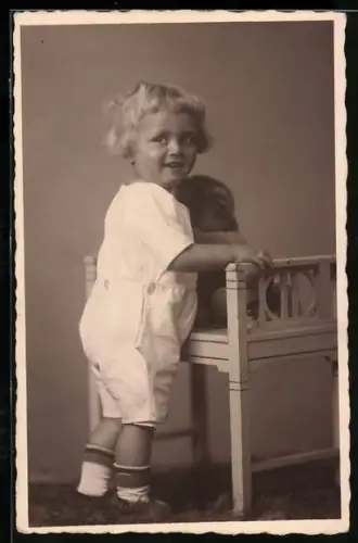 Foto-AK Kleinkind steht an einem Hocker mit Teddy