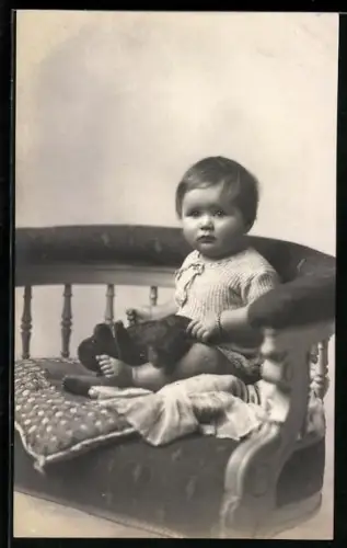 Foto-AK Kleinkind sitzt mit einem Teddy im Schoss auf einem Stuhl