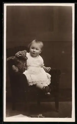 Foto-AK Kleinkind mit Teddy auf einem Stuhl sitzend 1921