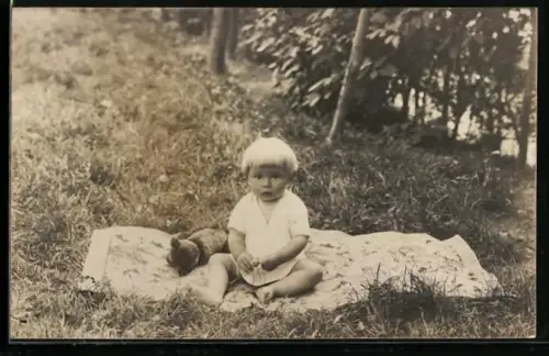 Foto-AK Junges Kind sitzt mit einem Teddy auf einer Wiese