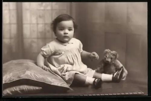 AK Kleinkind im Kleid sitzt mit einem Teddy auf einem Tisch