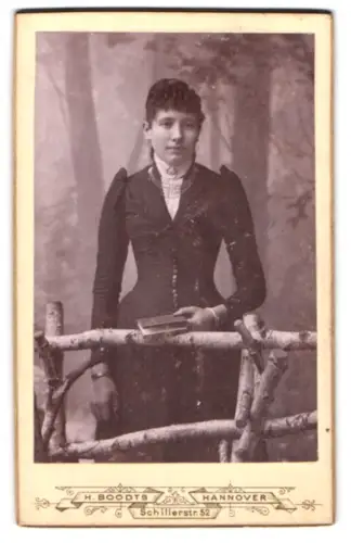 Fotografie H. Boodt, Hannover, Schillerstr. 52, Junge Frau mit Buch an einem rustikalen Geländer