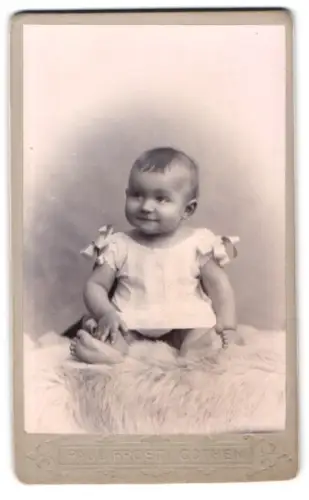 Fotografie Paul Frost, Cöthen, Lächelndes Kleinkind auf Fell