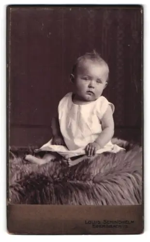 Fotografie Louis Schindhelm, Ebersbach i. S., Sitzendes Kleinkind auf Fell