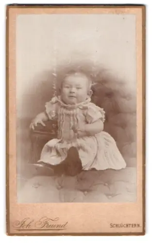 Fotografie Joh. Freund, Schlüchtern, Sitzendes Kleinkind auf Sofa