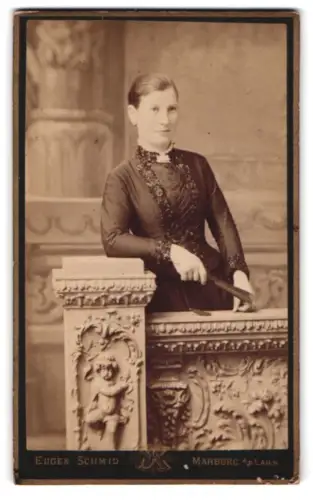 Fotografie Eugen Schmid, Marburg a. d. Lahn, Frau in dunklem Kleid an verziertem Geländer