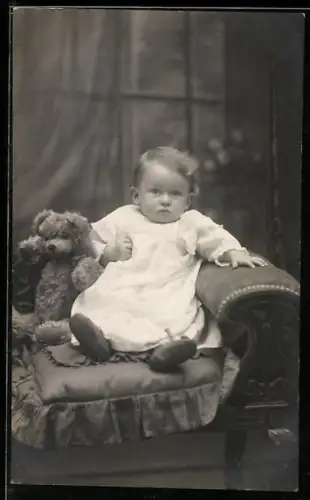 Foto-AK Kleinkind sitzt mit einem Teddy auf einem Sessel