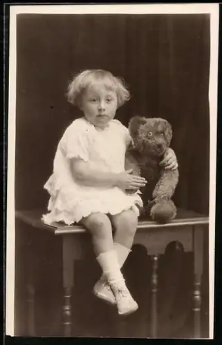 Foto-AK Kleinkind sitzt mit einem Teddy auf einem Tisch