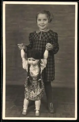 Foto-AK Kleines Mädchen mit Puppenmadchen bei Laufübungen