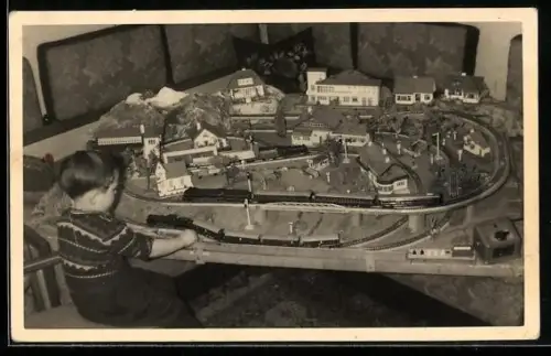 Foto-AK Kind mit Modell-Eisenbahnen auf Schienen