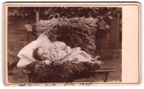Fotografie unbekannter Fotograf und Ort, Kleinkind auf Bank liegend