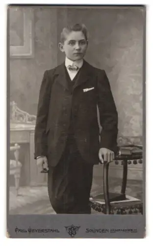 Fotografie Paul Weyerstahl, Solingen, Kasernenstrasse 17, Junge in Anzug neben Tisch