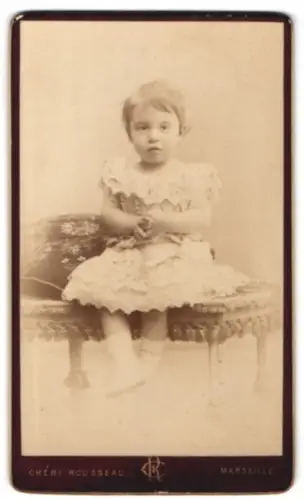 Fotografie Chéri Rousseau, Marseille, Rue Noailles 41, Kind in elegantem Kleid auf Sofa