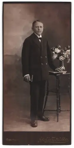 Fotografie Atelier Müller, Cossebaude, Junge im Anzug neben Blumenarrangement