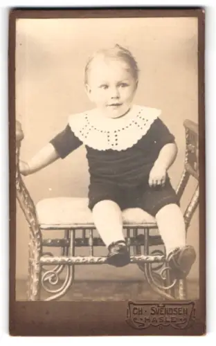 Fotografie Ch. Svendsen, Hasle, Sitzender Junge in dunkel gekleidetem Anzug