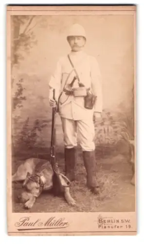 Fotografie Paul Müller, Berlin, Planufer 19, Grosswild-Jäger in tropischer Uniform mit seinem Jagdhund und Gewehr