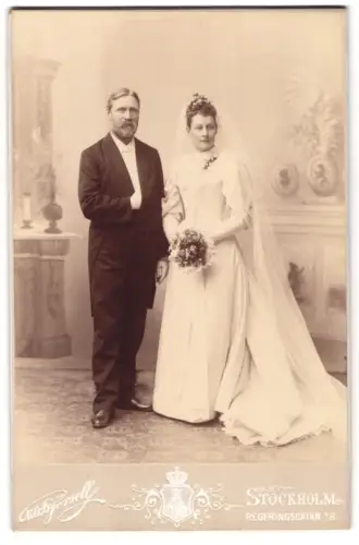 Fotografie Nils Hjörsell, Stockholm, Regeringsgatan 18, Elegantes Hochzeitspaar vor einer Studiokulisse