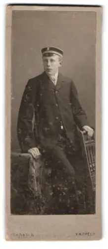 Fotografie L. Hansen, Kappeln, Student mit Tellermütze an einem Stuhl lehnend