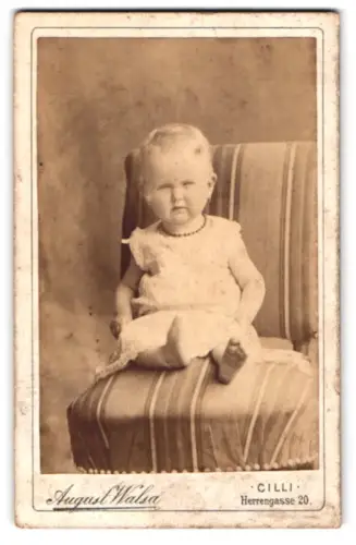 Fotografie August Walsa, Cilli, Herrengasse 20, Kleinkind auf gestreiftem Sessel