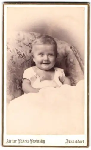 Fotografie Lüdcke-Lasinsky, Düsseldorf, Oststrasse 75, lächelndes Kleinkind auf einem Sessel