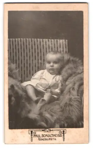 Fotografie Paul Schultheiss, Günzburg, Nächst dem Gymnasium, Kleinkind in Pelzdecke