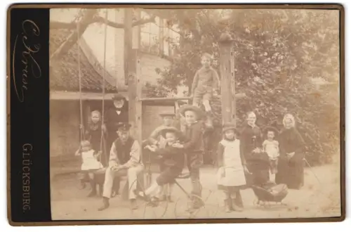 Fotografie C. Kruse, Glücksburg, Ansicht Glücksburg, Erwachsene und Kinder auf einem Spielplatz mit Dreirad und Schaukel
