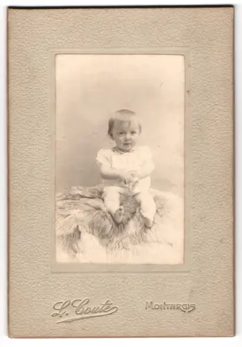 Fotografie L. Couté, Montargis, Porträt eines Kleinkindes auf Fell