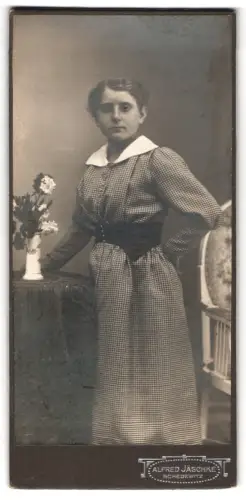 Fotografie Alfred Jäschke, Schedewitz, Frau in kariertem Kleid neben Blumenarrangement
