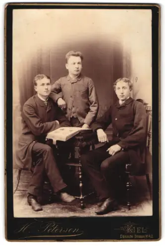 Fotografie H. Petersen, Kiel, Dänische Strasse 42, Drei junge Männer an einem Tisch