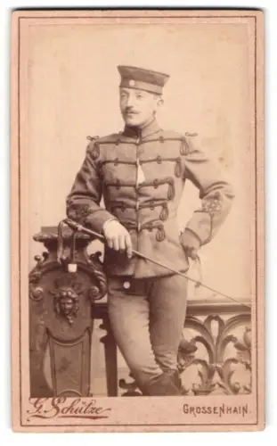 Fotografie G. Schütze, Grossenhain, Soldat der Husaren in Attila mit Dienstmütze und Reitgerte