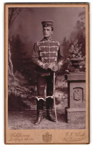 Fotografie G. F. Koch, Schleswig, Lollfuss 118-120, Soldat der Husaren in Attila mit Krätzchen und Säbel