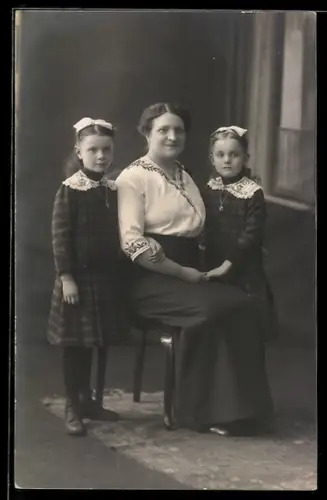 Foto-AK Frau mit zwei Mädchen in karierten Kleidern, Studiokulisse