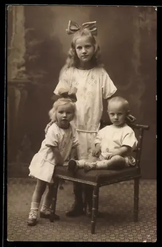 Foto-AK Mädchen im Kleid mit zwei Kleinkindern, Studiokulisse